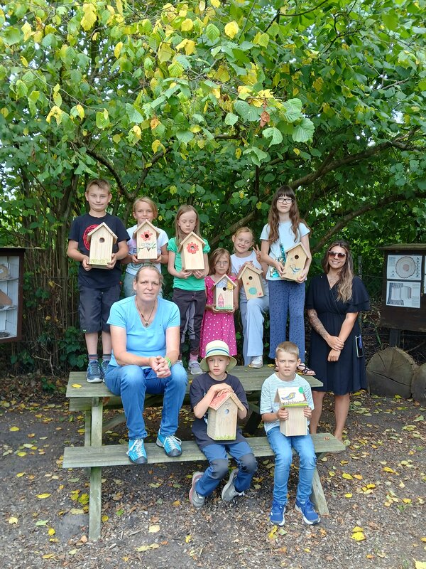 Eine Gruppe von Kindern zeigt stolz die selbgebauten und angemalten Nistkästen in die Kamera.