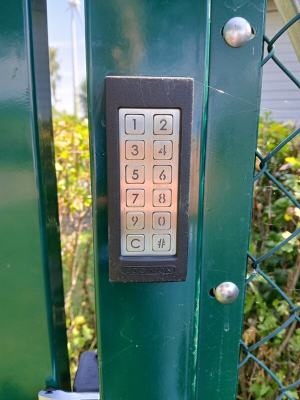 Tastenfeld in silber mit Zahlen von 0 bis 9, auf einem grünen Torpfosten angebracht